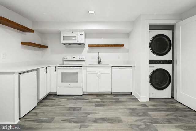 kitchen featuring sink, white appliances, white cabinetry, stacked washer / dryer, and dark hardwood / wood-style flooring