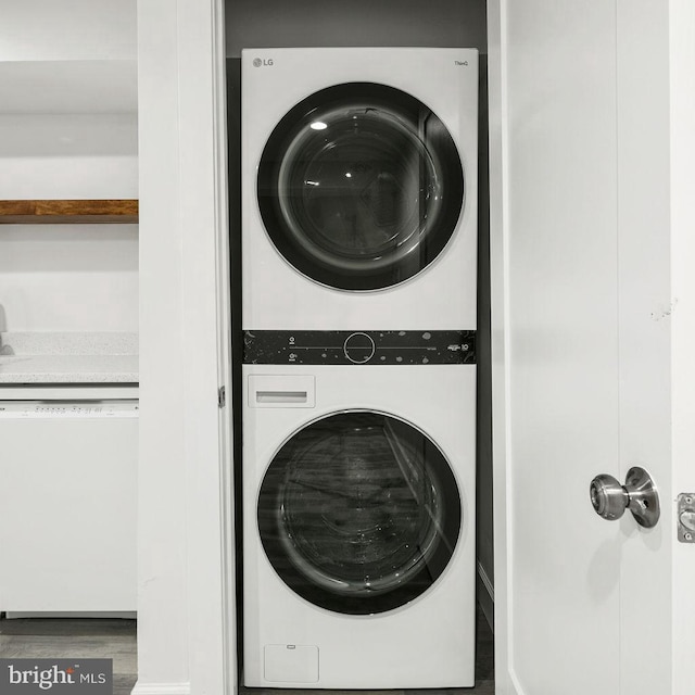 clothes washing area with wood-type flooring and stacked washer and clothes dryer