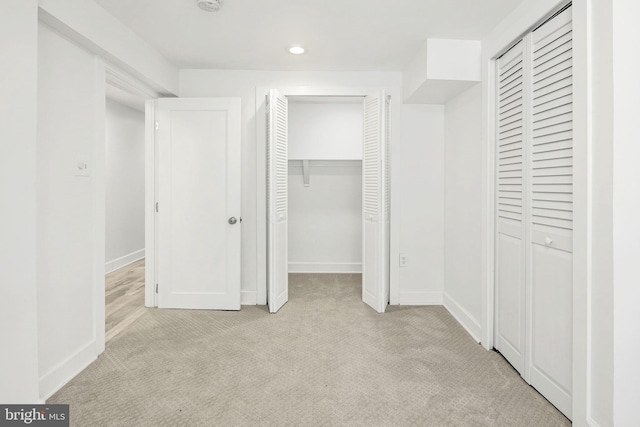 unfurnished bedroom featuring multiple closets and light carpet