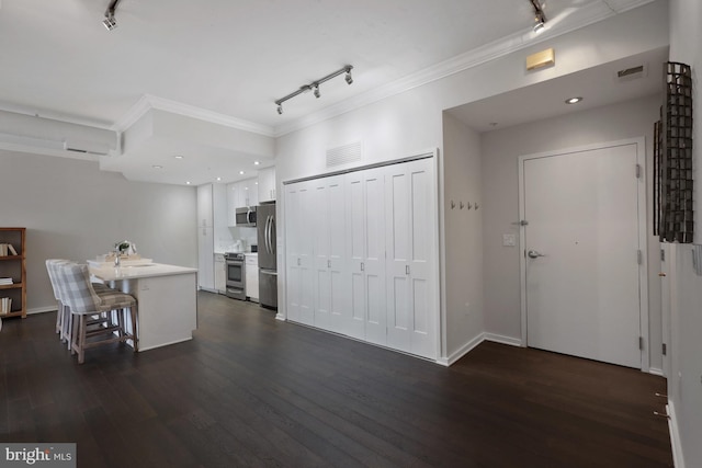 kitchen featuring dark wood-type flooring, a kitchen bar, white cabinetry, crown molding, and stainless steel appliances