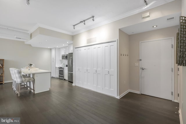 kitchen with a breakfast bar area, crown molding, dark hardwood / wood-style flooring, stainless steel appliances, and white cabinets