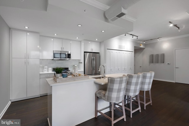 kitchen featuring a breakfast bar, appliances with stainless steel finishes, white cabinetry, a kitchen island with sink, and dark hardwood / wood-style floors