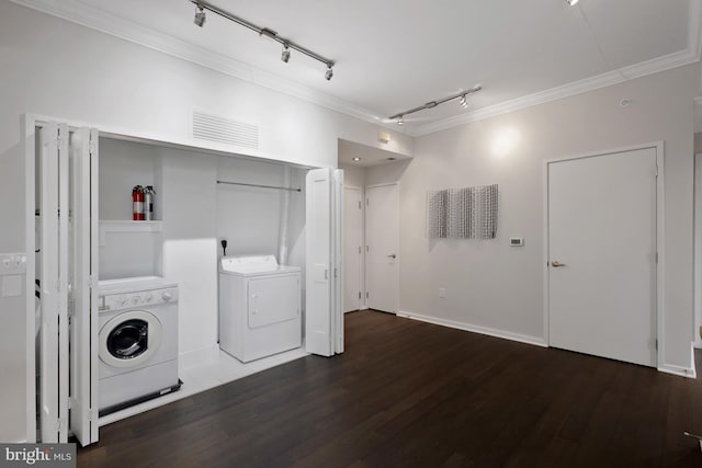 laundry room featuring crown molding, dark wood-type flooring, and washing machine and clothes dryer