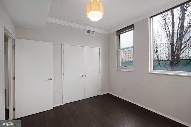 unfurnished bedroom featuring ornamental molding, dark hardwood / wood-style flooring, and a closet