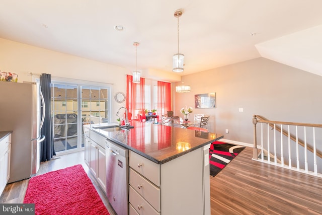 kitchen with stainless steel appliances, sink, a kitchen island with sink, and dark hardwood / wood-style flooring