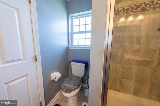 bathroom featuring a shower with door and toilet