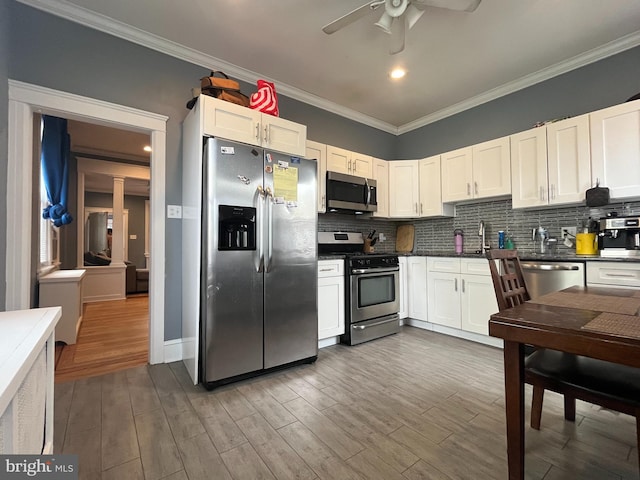 kitchen featuring appliances with stainless steel finishes, dark hardwood / wood-style floors, white cabinets, decorative backsplash, and crown molding