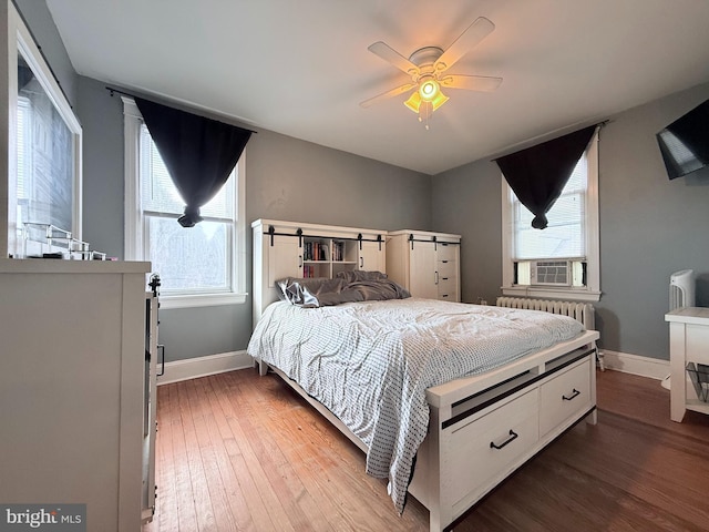 bedroom featuring hardwood / wood-style flooring, radiator, cooling unit, and ceiling fan