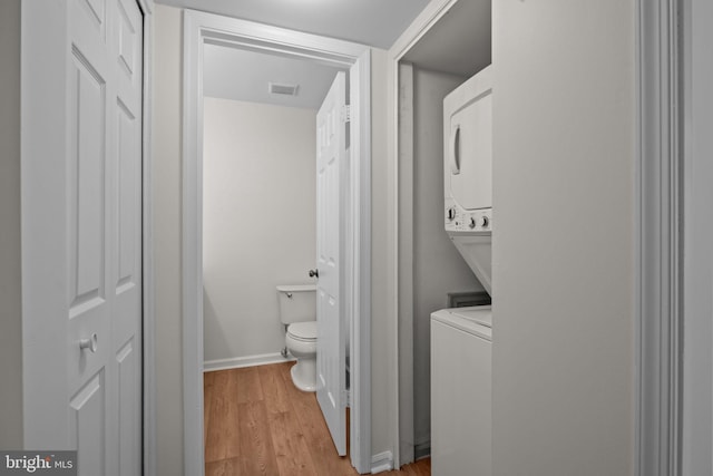 washroom featuring light hardwood / wood-style flooring and stacked washer and clothes dryer