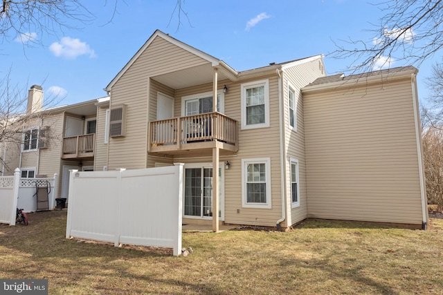 rear view of house with a balcony and a lawn