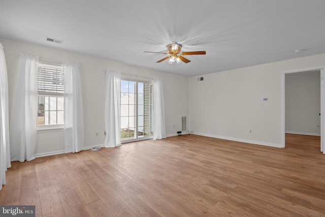 empty room with ceiling fan, plenty of natural light, and light hardwood / wood-style floors