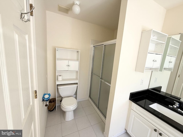 bathroom featuring tile patterned floors, toilet, a shower with door, and vanity