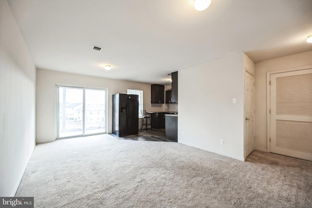 unfurnished living room with carpet floors and visible vents