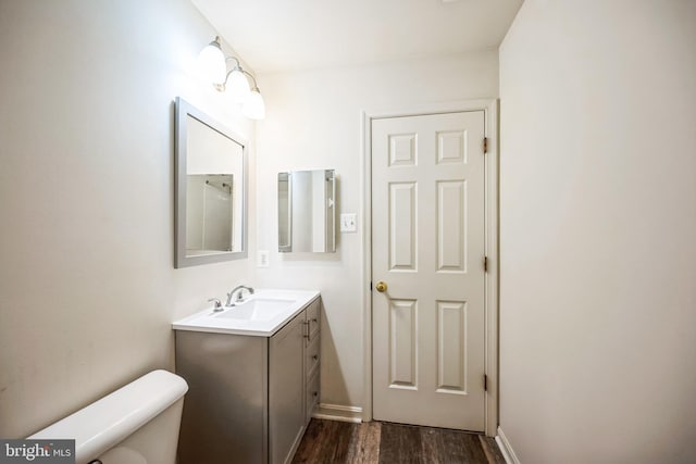 bathroom featuring toilet, wood finished floors, and vanity