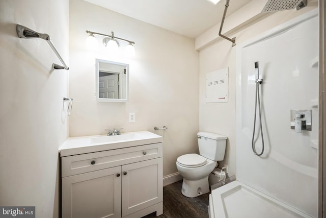 bathroom with wood finished floors, vanity, toilet, and walk in shower