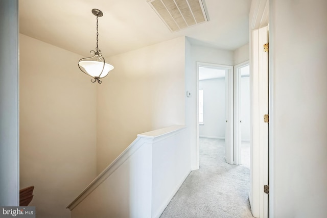 corridor featuring visible vents, carpet flooring, and an upstairs landing