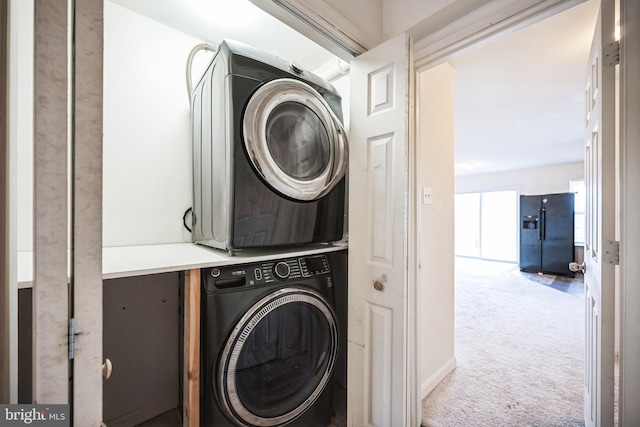 washroom featuring laundry area, stacked washer / dryer, and carpet