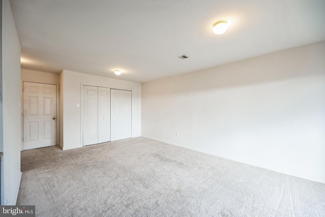 unfurnished bedroom featuring carpet, visible vents, and a closet