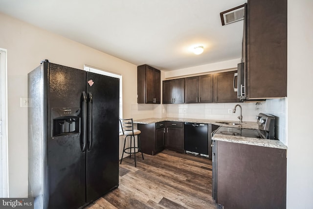 kitchen with dark brown cabinetry, tasteful backsplash, visible vents, dark wood-type flooring, and black appliances