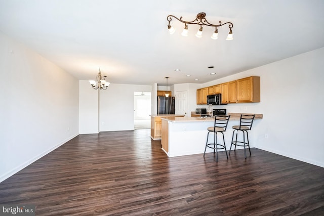 kitchen with freestanding refrigerator, black microwave, dark wood finished floors, and a peninsula