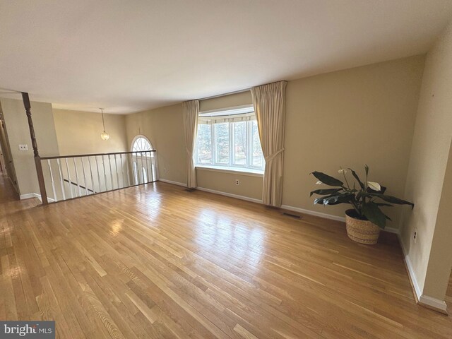 unfurnished room with visible vents, baseboards, and wood finished floors