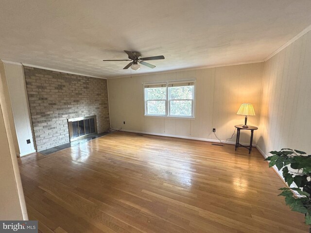 unfurnished living room with crown molding, a fireplace, ceiling fan, and wood finished floors