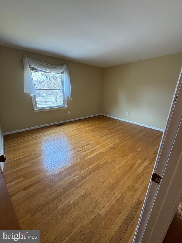 spare room with visible vents, light wood-style flooring, and baseboards