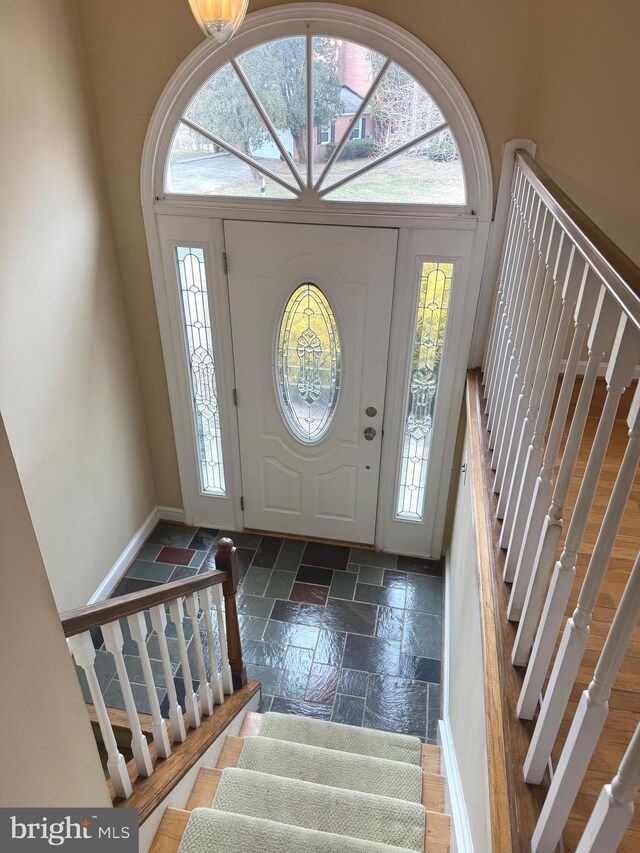 entryway featuring stairway, a towering ceiling, and stone tile floors