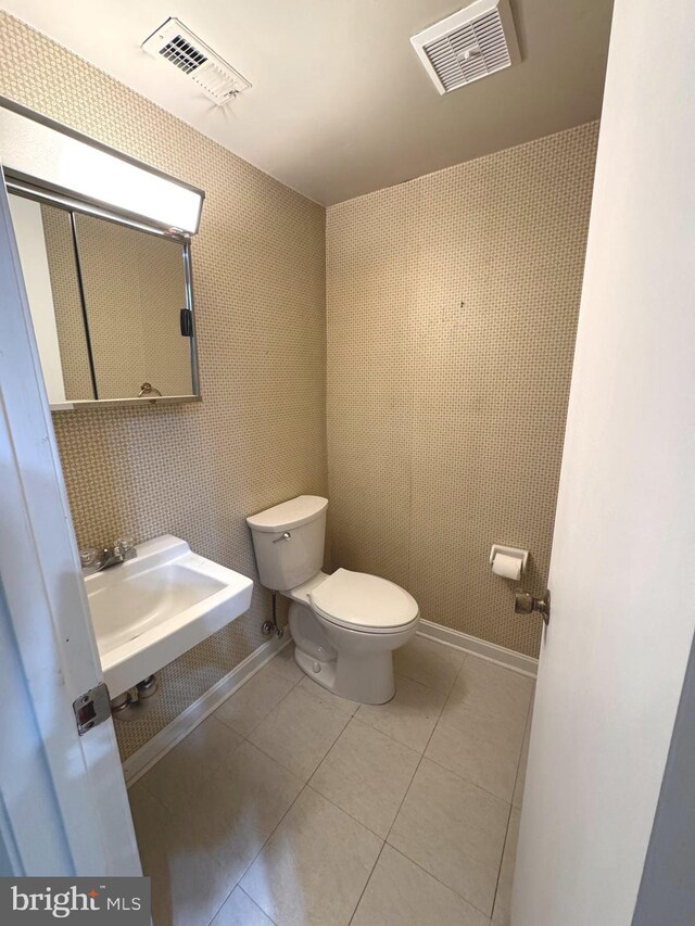 bathroom with toilet, tile patterned flooring, a sink, and visible vents