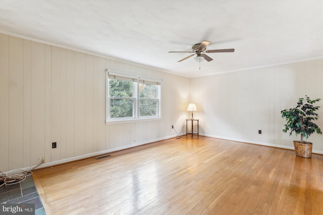 empty room with baseboards, visible vents, ceiling fan, ornamental molding, and wood finished floors