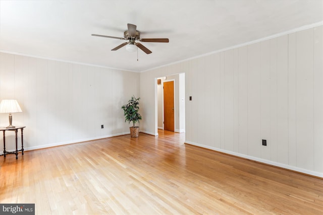 empty room with ceiling fan, ornamental molding, light wood-type flooring, and baseboards