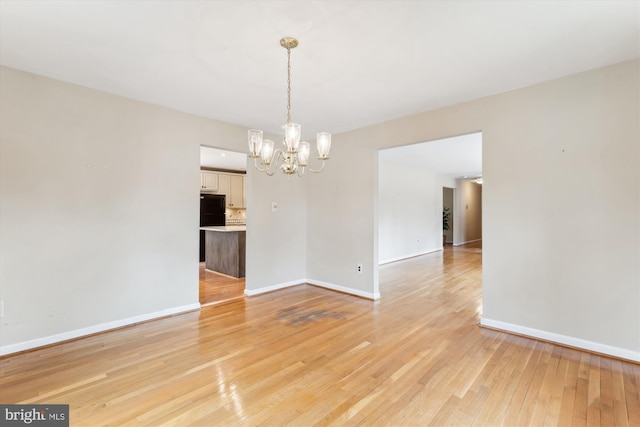 unfurnished dining area featuring light wood-type flooring, baseboards, and an inviting chandelier