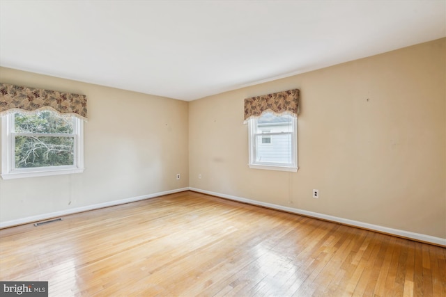 empty room with baseboards, visible vents, and wood finished floors