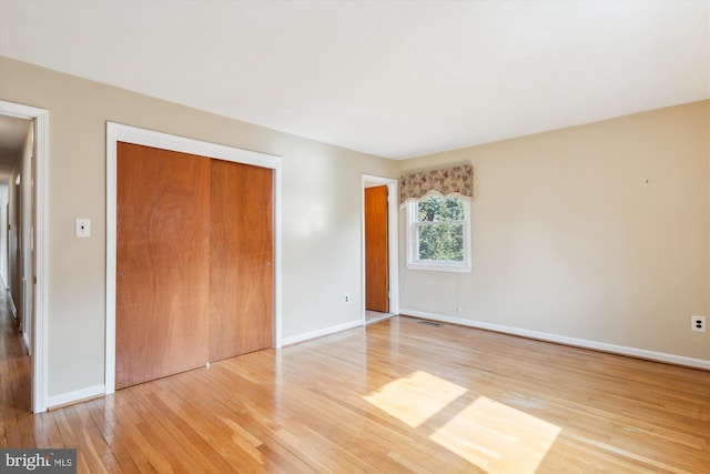 unfurnished bedroom featuring a closet, baseboards, and wood finished floors