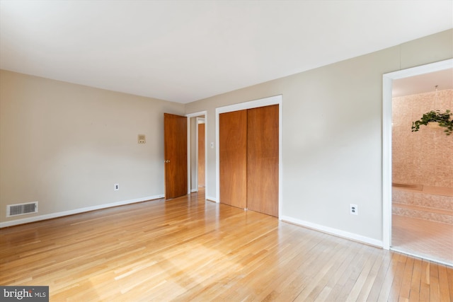 unfurnished bedroom featuring light wood-style flooring, a closet, visible vents, and baseboards