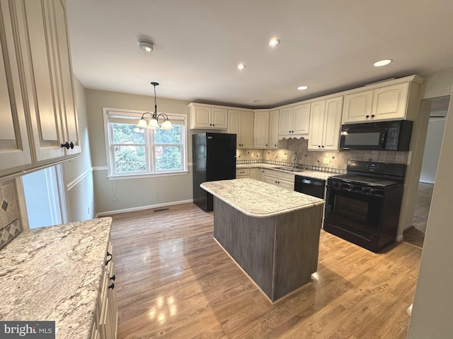 kitchen featuring tasteful backsplash, light wood-type flooring, light stone counters, and black appliances