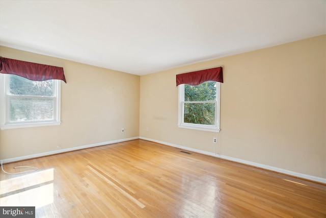 empty room featuring baseboards, visible vents, and wood finished floors