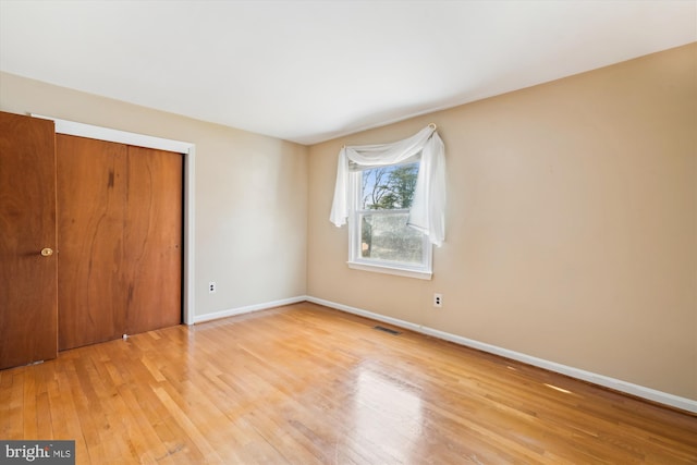 unfurnished bedroom with baseboards, a closet, visible vents, and light wood-style floors