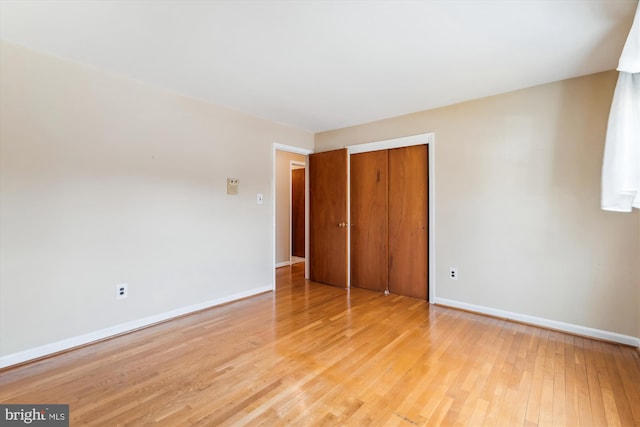 unfurnished bedroom with light wood-type flooring, a closet, and baseboards