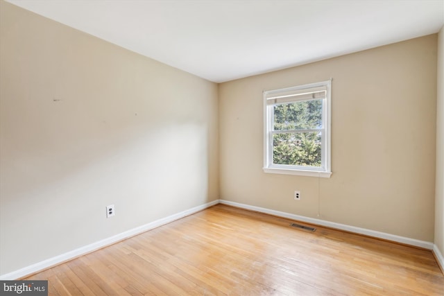 empty room featuring light wood finished floors, visible vents, and baseboards