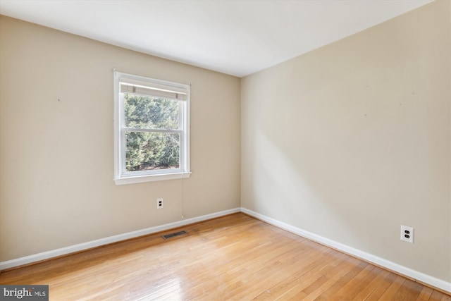 spare room featuring baseboards, visible vents, and light wood-style floors