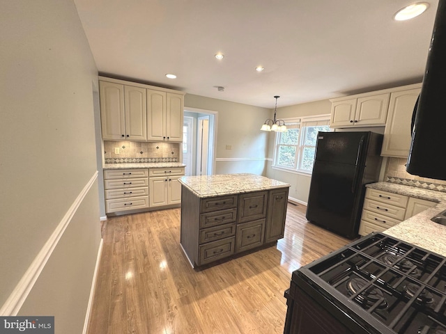 kitchen with light stone counters, light wood-type flooring, cream cabinetry, and black appliances