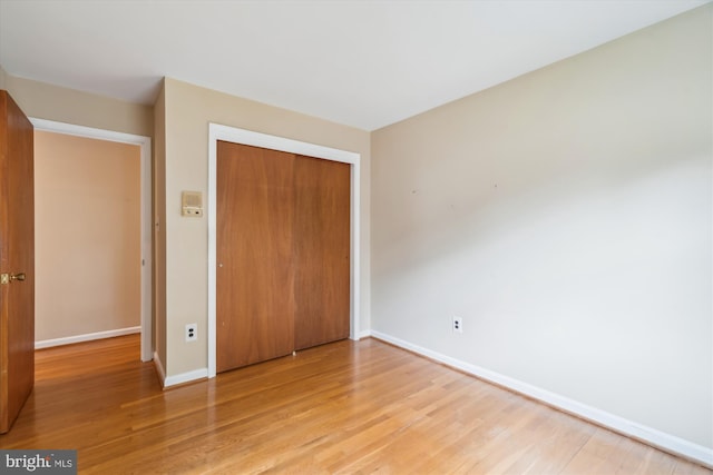 unfurnished bedroom with a closet, light wood-style flooring, and baseboards