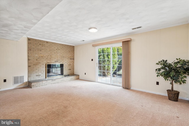 unfurnished living room with a brick fireplace, carpet flooring, and visible vents