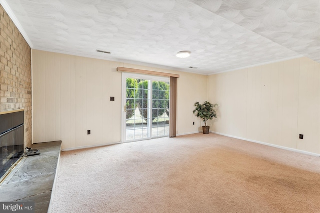 unfurnished living room with a fireplace, visible vents, baseboards, carpet, and crown molding