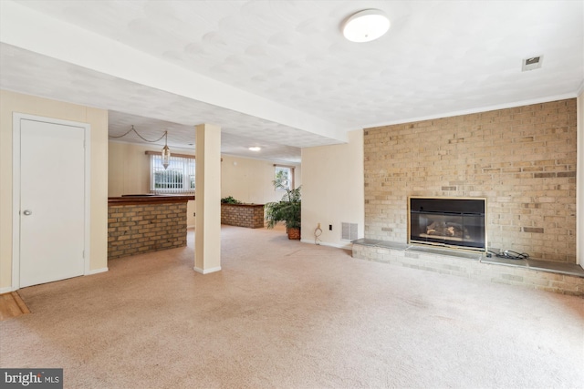 unfurnished living room with a brick fireplace, visible vents, baseboards, and brick wall