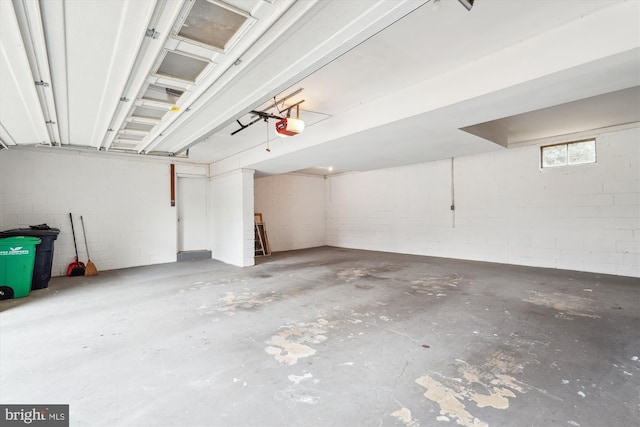 garage featuring concrete block wall and a garage door opener