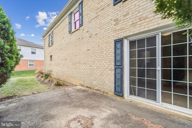 view of side of property with brick siding and a patio