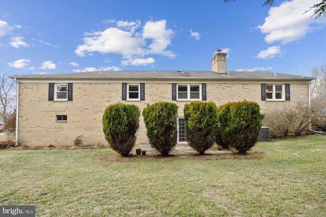 back of property featuring brick siding, a lawn, a chimney, and central air condition unit