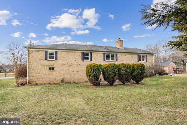 view of side of home featuring a yard, brick siding, and a chimney